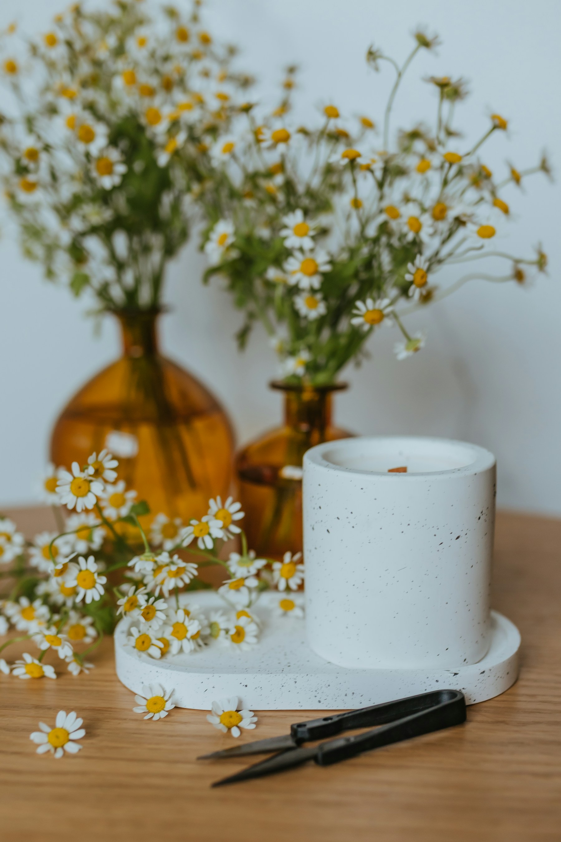 Chamomile flowers arranged with amber bottles and a candle